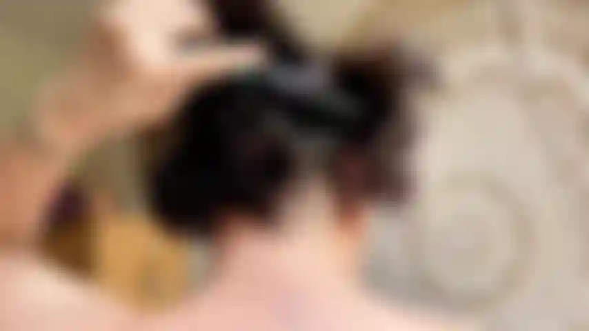 Spazzolare i capelli con la testa del pettine e orecchini da vicino.