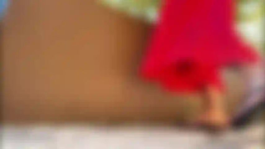 Vestito rosso con gonna rialzata, infradito con punte rosse e rosa.