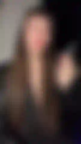 La dea emily che fuma, vestita di pelle e pizzo, con le labbra rosse.