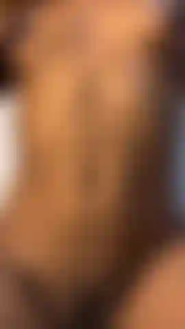 Una ragazza che si ricopre il corpo di olio mentre gioca con la sua fica pelosa nel suo soggiorno.