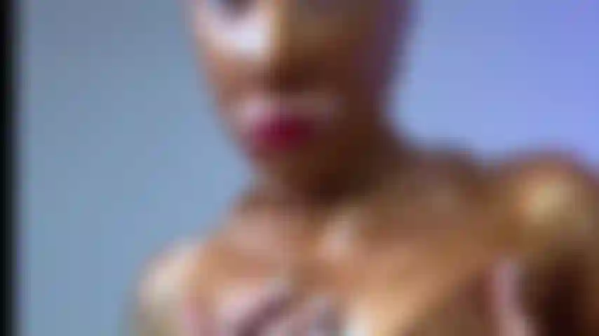 Il corpo in tuta di lattice dorata stuzzica con la figa esposta.