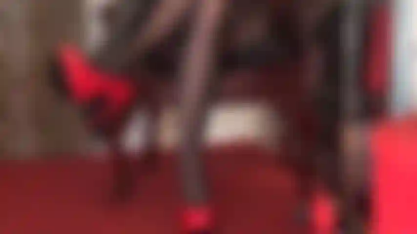 Tacchi a spillo rossi lucidi, guanti di pelle nera e collant neri sono pura seduzione.