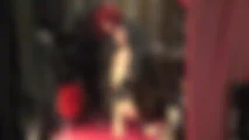 Una dea in pelle che ti stuzzica con le sue gambe sexy in collant color cuoio lucido e sandali rossi con cinturino alla caviglia.