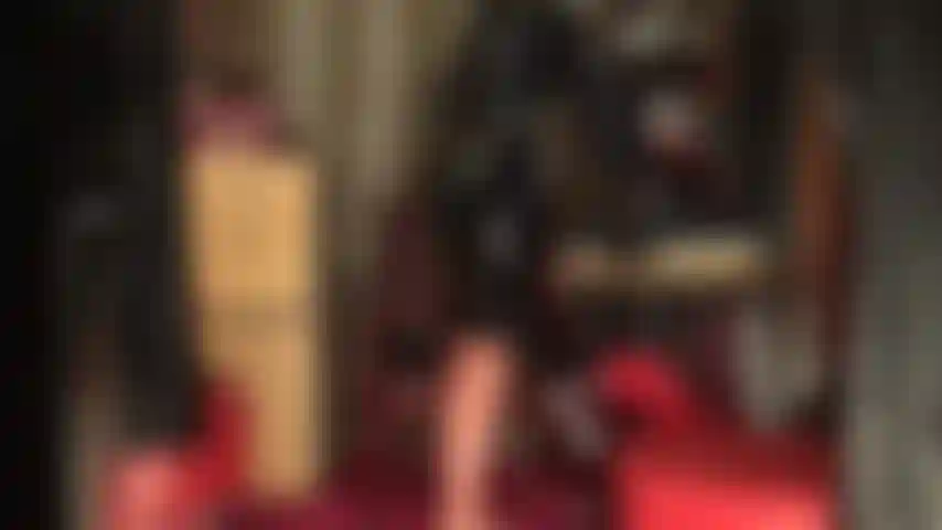 Abito in gomma lucida, calze e maschera: una dea mostra le sue curve in lattice attillato, calze trasparenti con cuciture e gonna a tubino nera con guanti. L'abito è completato da una maschera in lattice.