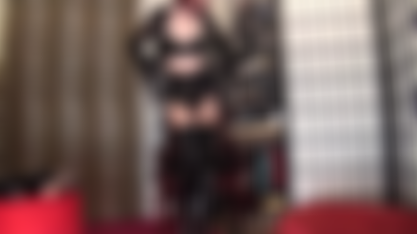 In lingerie provocante con reggiseno in lattice, calze lucide, calze autoreggenti, giarrettiere, stivali e tacchi.