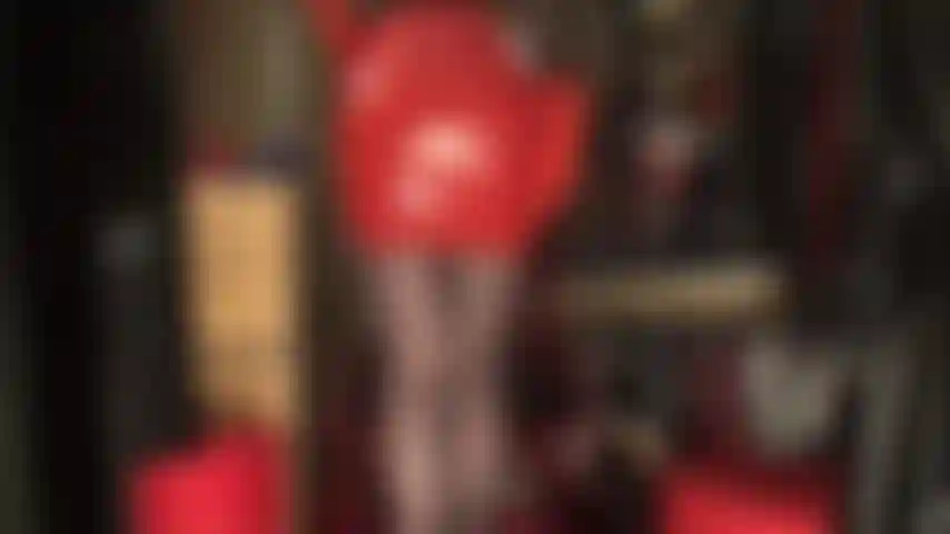 Con una gonna sexy in lattice rosso, guanti di gomma, collant neri e tacchi rossi.