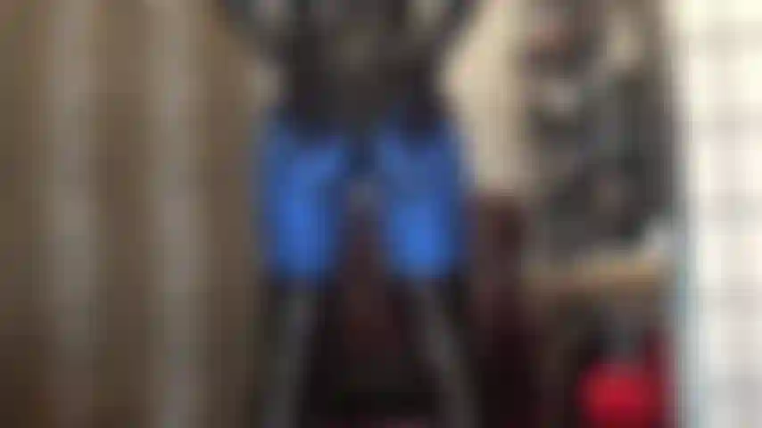 Culo in leggings in lycra blu metallizzato e body in pvc lucido, piedi in collant marrone scuro.