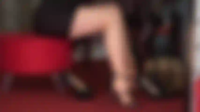 Seducente con gambe e piedi in collant abbronzati e diverse paia di sexy tacchi alti neri.