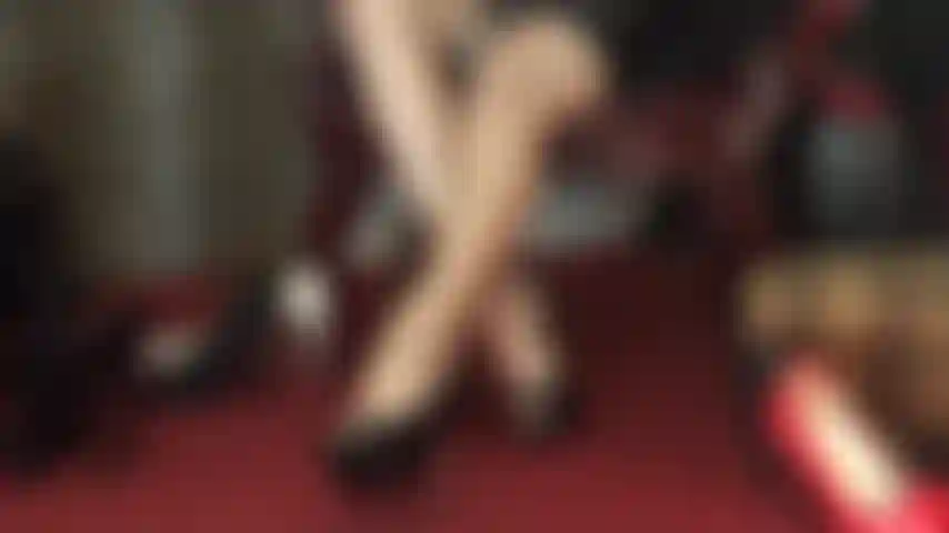 Pura seduzione: lunghe gambe incrociate che si chiudono e si aprono in collant lucidi, regalando visioni allettanti nel mezzo.