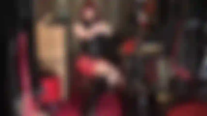 Feticista del lattice: abito in gomma rossa e nera con stivali al ginocchio.