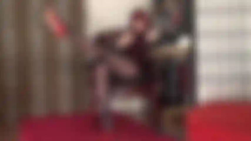 Con lunghe gambe in collant, giochi con le scarpe e tacchi a spillo rossi penzolanti, feticismo dei piedi.