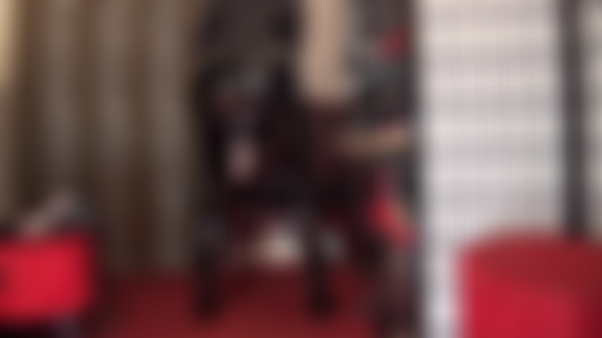 Una dea in pvc con una tuta nera lucida che mi stuzzica con il suo enorme pene bianco con strap-on che spunta da sotto la gonna.