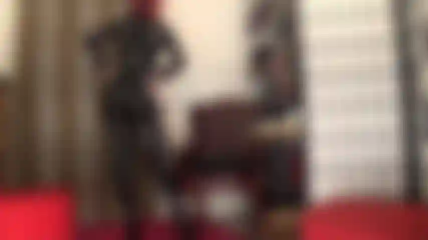 In una tuta attillata in pvc nero, corsetto e stivali alti fino alla coscia.