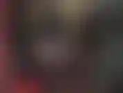 Una mistress perversa in lattice con cappuccio, guanti, stivali e un grande strapon bianco.