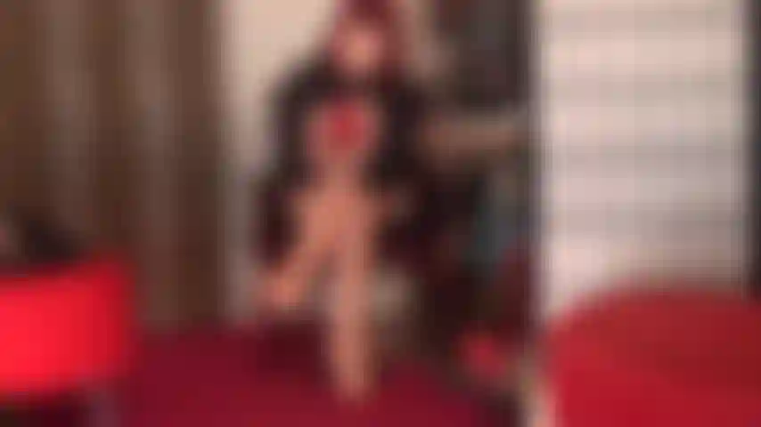 Seducente in rosso: la padrona vivian indossa un paio di calze rosse con la bretella in pizzo sopra collant color carne lucidi, décolleté rosse con tacco a spillo e guanti in pelle rossa.