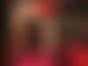 Provocazione sensuale e adorazione del corpo in rosso e nero: la padrona indossa un abito sexy con corsetto in pelle, collant lucidi color carne e décolleté rosse lucide.