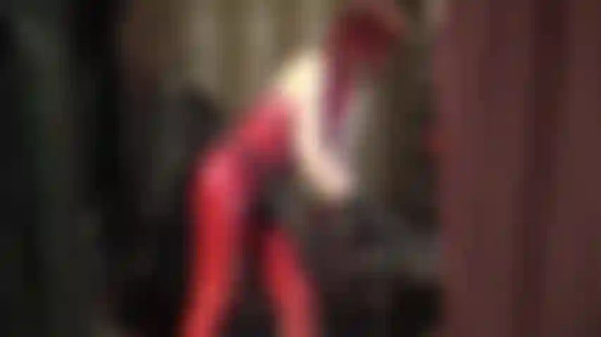 Con uno strapon nero enorme e una tuta di gomma rossa.