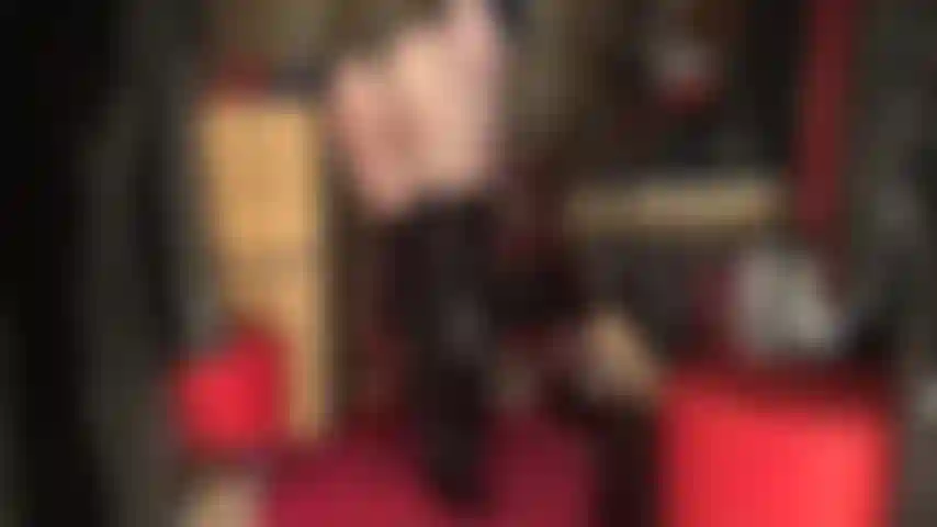 Una dea che adora il culo in un body in pvc nero lucido con perizoma e stivali alti sopra collant neri trasparenti.