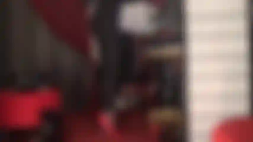 Indosso tacchi a spillo rossi fetish e perizoma in pizzo rosso su una tuta attillata nera.