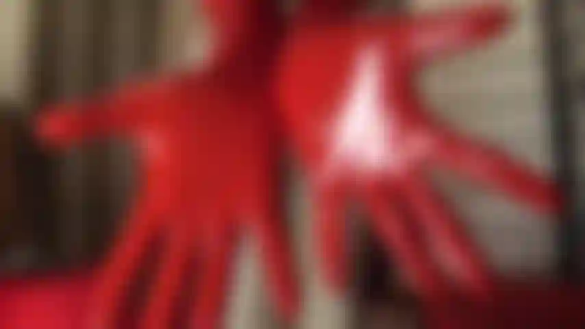 Feticista della gomma: la padrona vivian indossa abiti attillati in lattice, gonna corta sopra calze lucide, guanti e cappuccio di gomma completo.