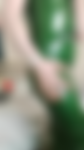 Il video di un cliente in lattice è una chat con un vestito in lattice verde attillato, in piedi e seduta che mostra le cerniere del vestito - nessuna nudità.