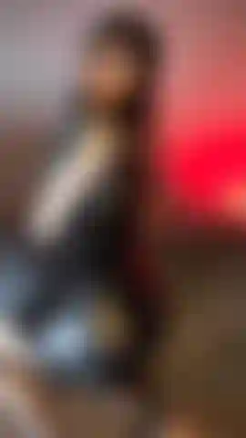 Una ragazza sexy e tatuata che indossa un abito di pelle nera, calze a rete e si sculaccia il sedere.