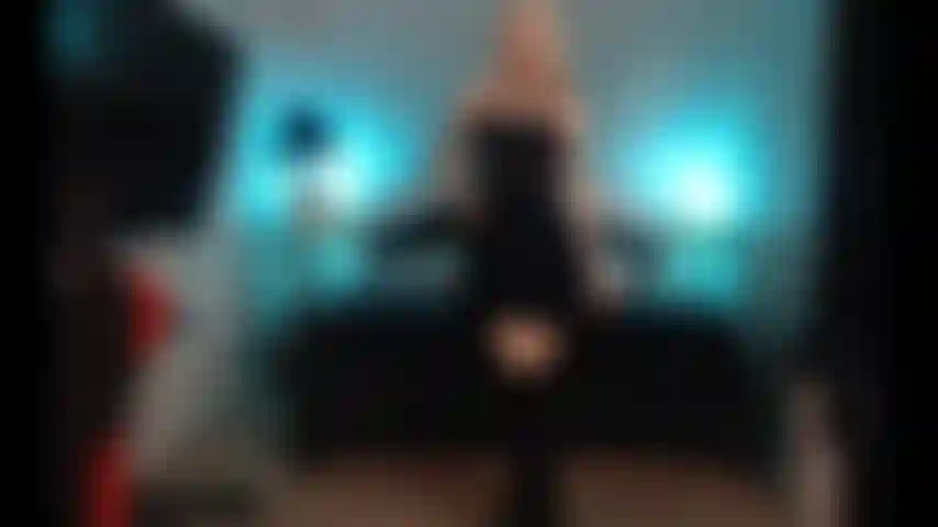 Cumming, con indosso un vestito nero e stivali.