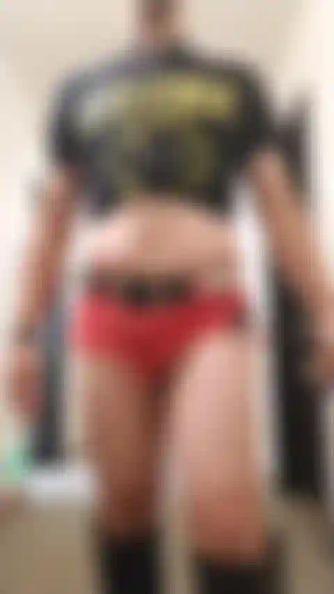 Travestito in posa sexy nel corridoio dell'hotel con indosso pantaloncini di jeans e stivali.